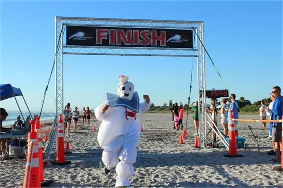 Race participant crossing the finish line dressed as the Stay Puft Marshmallow Man